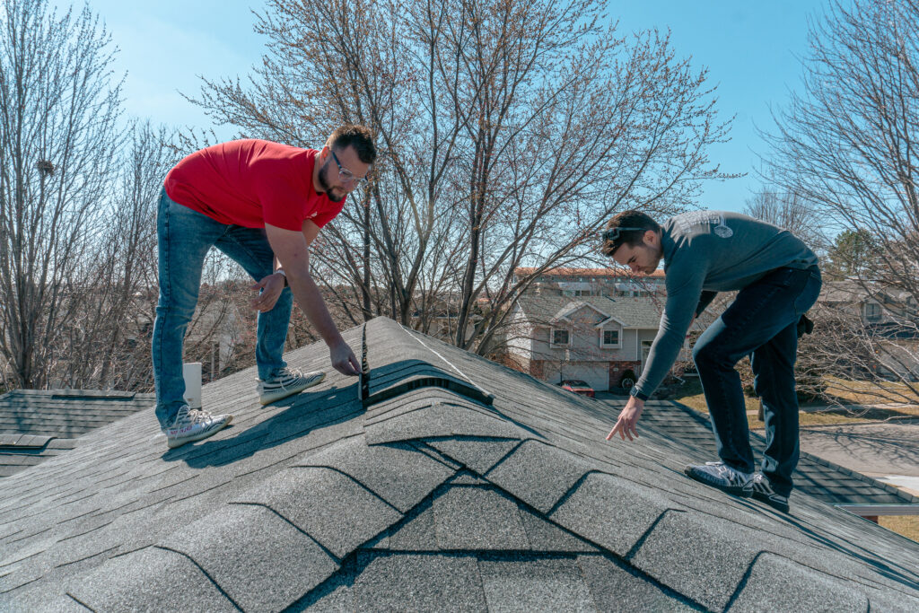 Image capturing two professionals inspecting a roof.